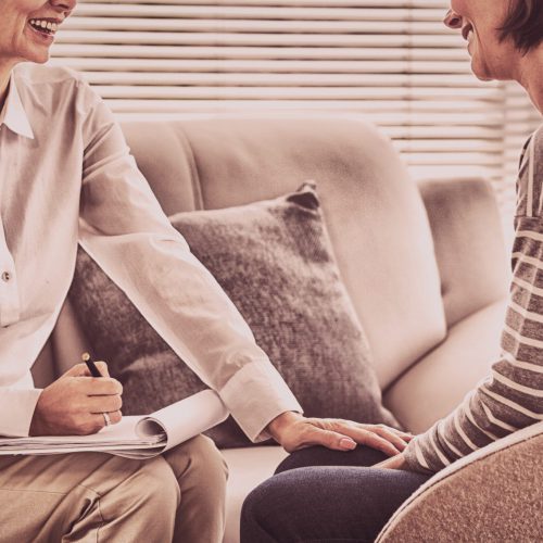 Happy therapist with patient on sofa at home
