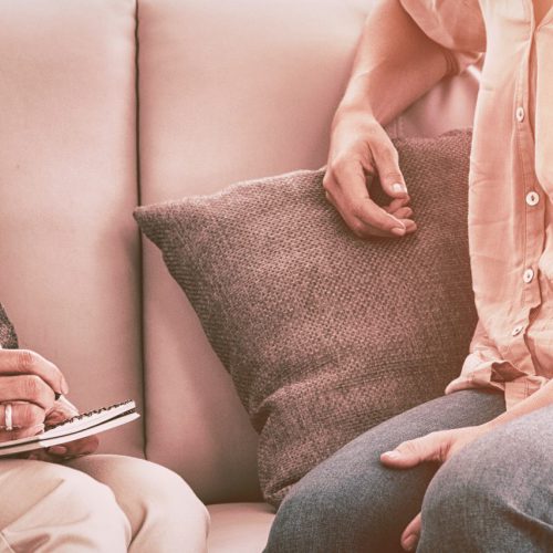 Smiling woman talking to therapist on sofa at home